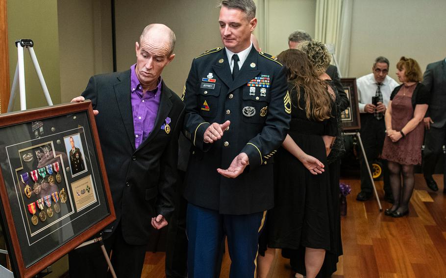 Retired Army Staff Sgt. Michael Thomas Jeffrey, left, reacts with surprise after seeing a glass-encased framed board with his military service medals presented to him as a gift after he received a Purple Heart during a ceremony in Washington D.C. on Purple Heart Day on Tuesday, Aug. 7, 2018. Applauding is Jeffrey's brother, Army Sgt. 1st Class Joe Jeffrey.