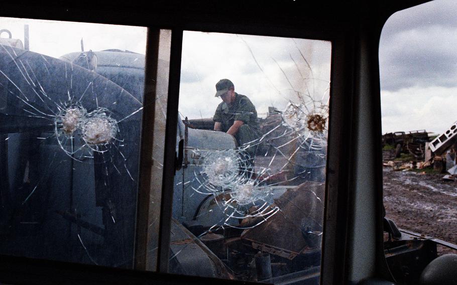 A worker at the Long Binh Army Depot's salvage yard is seen through the bullet-riddled windows of a vehicle in 1968.