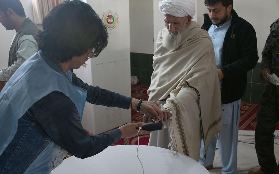 A man places his finger on a biometric machine at a voting center in Kabul before casting his ballot in the country's parliamentary elections on Sunday, Oct. 21, 2018. Voting at the center was extended from Election Day on Saturday, partly because of problems with the machines. 
