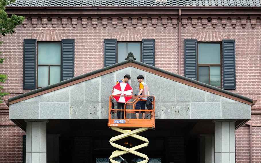 South Korean workers remove the signage from Eighth Army's former headquarters at Yongsan Garrison in Seoul, South Korea, July 10, 2017. 
