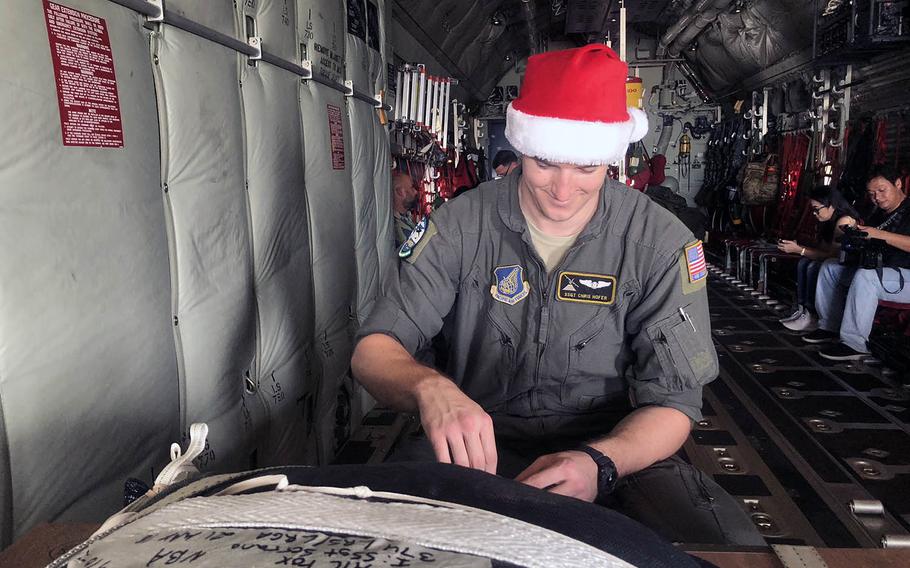 Staff Sgt. Chris Hofer, a loadmaster from Yokota Air Base, prepares a box of Operation Christmas Drop donations on board a C-130 Super Herc on Dec. 9, 2018.