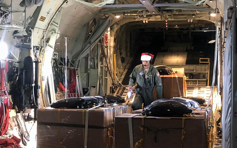 Senior Airman Walter Frank makes a final check of the Operation Christmas Drop donation boxes before a flight over the Northern Mariana Islands. The black bags atop the boxes contain parachutes. 