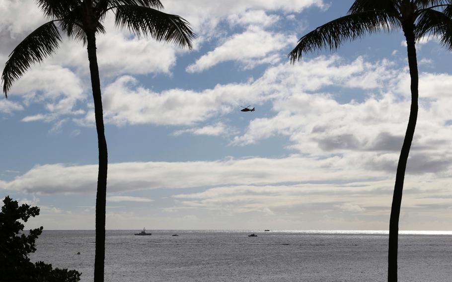A U.S. Coast Guard helicopter flies over rescue boats at the scene of a Hawker Hunter crash off Honolulu, Wednesday, Dec. 12, 2018. 