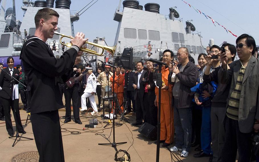 In a 2009 file photo, Petty Officer 2nd Class Collin Reichow plays a trumpet solo on the pier at Qingdao for Chinese citizens waiting to tour the guided-missile destroyer USS Fitzgerald during the International Fleet Review celebrating the 60th anniversary of the founding of the People's Liberation Army navy. The Pentagon says the U.S. won't be taking part in the 70th anniversary events this year.