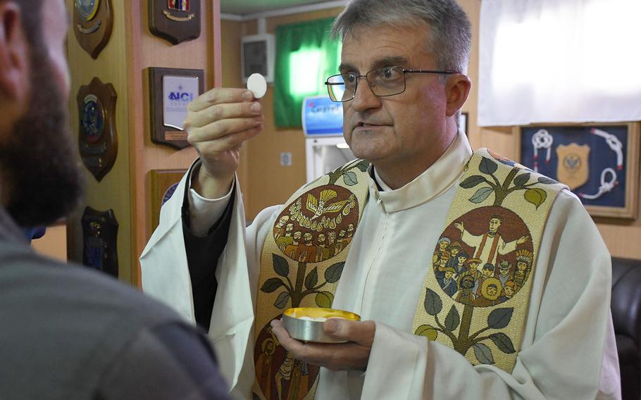 Father Giovanni Scalese, chaplain at the Italian Embassy in Kabul, distributes communion at a Catholic Easter mass at NATO's Resolute Support headquarters in the Afghan capital on April 21, 2019.