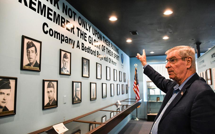 Ken Parker points toward the photos of 19 men, known as the 'Bedford Boys' who were killed in action during the invasion of Normandy. The photos take up one wall of the Bedford Boys Tribute Center, which Parker and his wife, Linda, opened in May in downtown Bedford, Va. Nikki Wentling/Stars and Stripes
