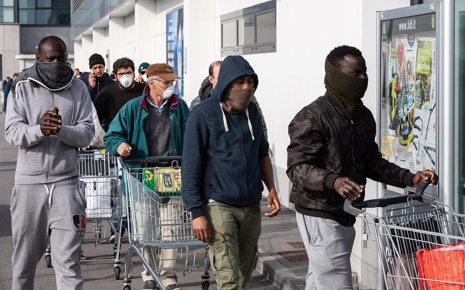 People wearing respiratory masks wait to be given a 10-minute access to shop in a LIDL supermarket in groups of 20 people on Sunday, Feb. 23, 2020 in Casalpusterlengo, southwest Milan, Italy.
