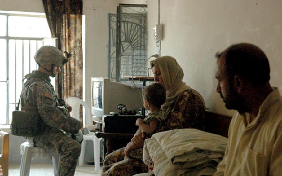 Spc. John Schroeder, 21, of Lancaster, Pa., examines an Iraqi family’s software CDs in western Ramadi recently to see if they contained images of insurgent videos.