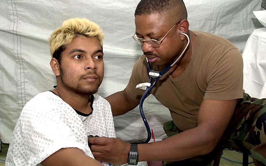 Air Force Capt. Mervin Howe from the 374th Medical Group at Yokota Air Base, Japan, treats a patient Sunday in a field hospital set up to help support civilians on Guam in the aftermath of a super typhoon.