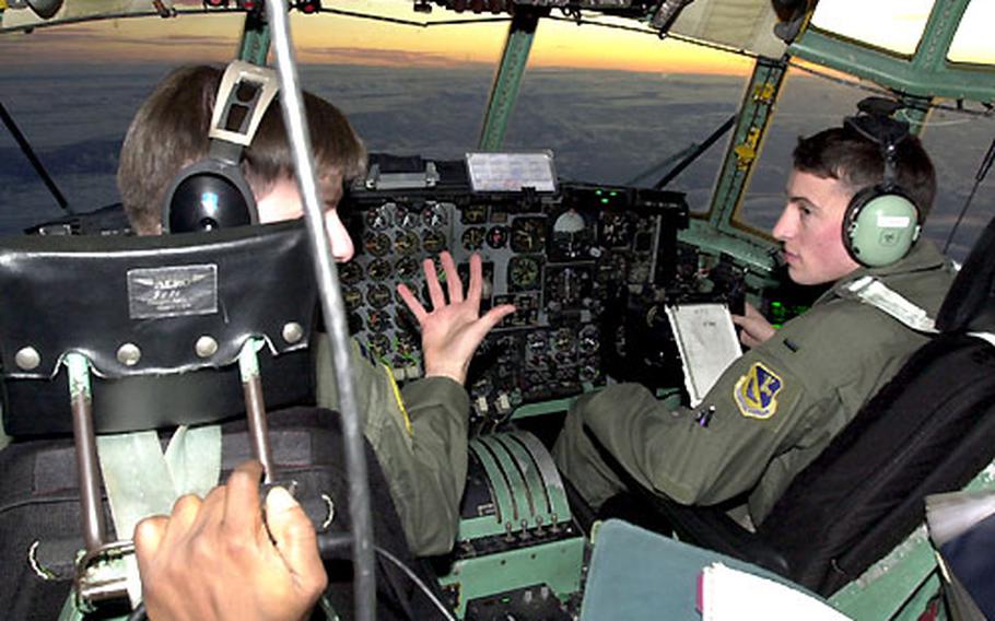 1st Lt Peter Thern, right, and his pilot, Capt. William Hollyfield, discuss flight info on a C-130. The plane, from Yokota&#39;s 36th Airlift Squadron, was carrying the 374th Medical Group from Yokota Air Base to Guam.
