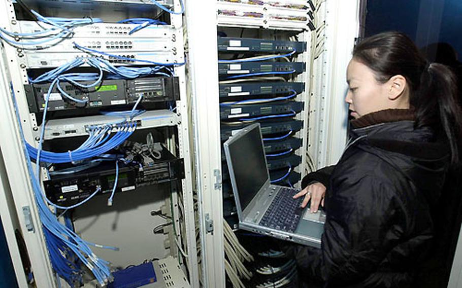 Sachiko Sugita, assistant network engineer with JENS Corp., uses a laptop computer to perform a systems check on equipment installed by the company at Misawa Air Base, Japan, that delivers ADSL Internet service to customers at the northern Honshu installation.