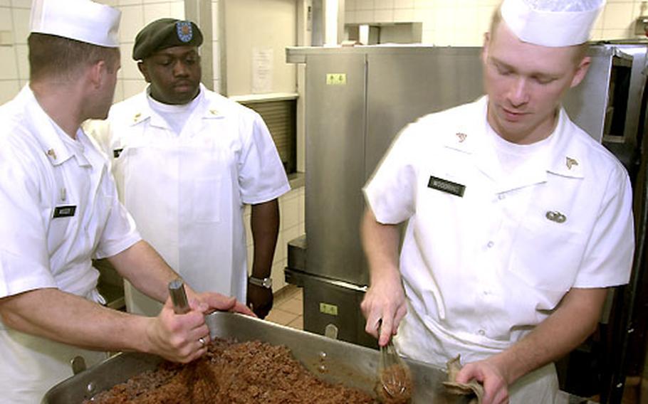Sgt. 1st Class Trevin McLeod, Kelly Barracks Dining Facility manager, center, stops to talk to Sgt. Donald Moser and Sgt. Robert Woodring as they prepare ground beef for a Mexican lunch on Tuesday at Kelly Barracks, Germany.