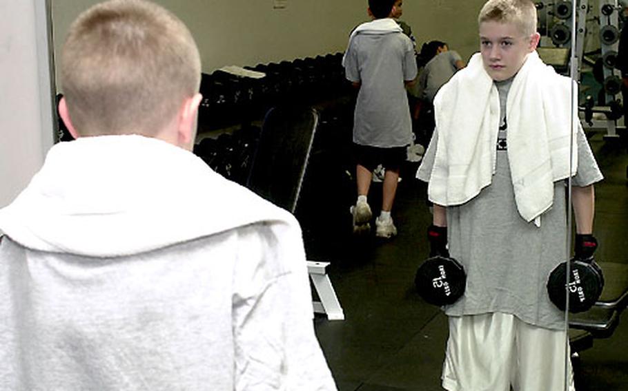 Nathan Sherman lifts a pair of dumbbells while watching his form in a mirror at the Yano Fitness Center.