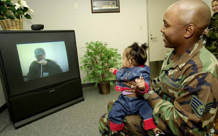 Alofania Taylor appears distracted as her father, Staff Sgt. Tim Taylor, enjoys a few moments talking with his wife, Rica, a staff sergeant deployed to Prince Sultan Air Base, Saudi Arabia. The video teleconferencing room at Misawa Air Base, Japan, is proving to be popular with families of deployed troops during the holiday season.