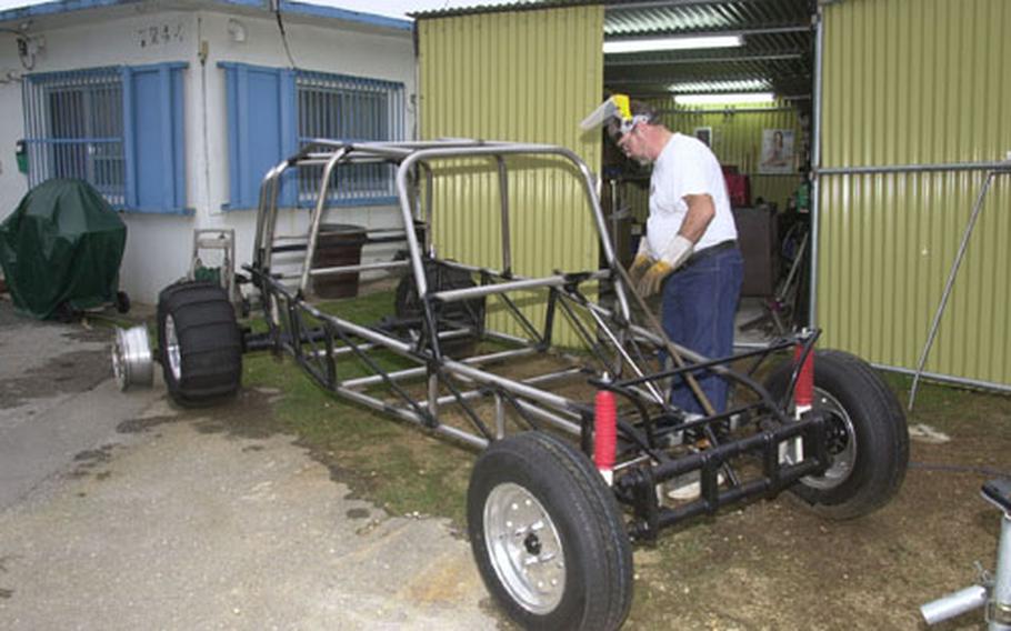 Kurt Lusso, a civilian contractor on Kadena Air Base, attaches a specially-fit tube onto the frame of a dune buggy, one of two off-road vehicles he&#39;s building in his spare time.