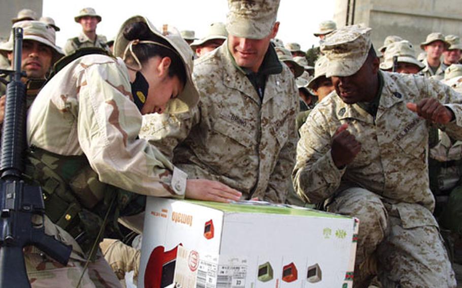Corp. Veronica Chambless opens a gift Christmas Eve as fellow I Marine Expeditionary Force members Lt. Col. Kirk Bruno, left, and Sgt. Maj. Rick Hines, watch.