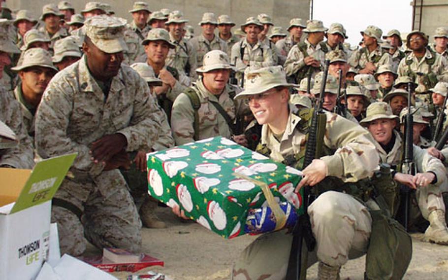 Corp. Allison Benoit gets ready to unwrap a Christmas gift as fellow I Marine Expeditionary Force members look on at Commando Camp in Kuwait.