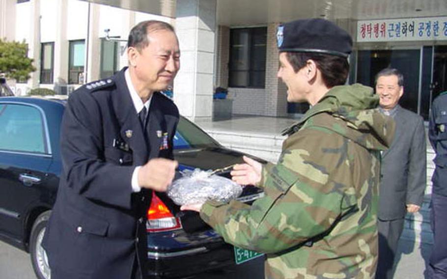 Police Chief Lee Kwang-young of the Korean National Police receives one of the 136 pies dropped off at Nambu police station in Taegu, South Korea by soldiers from U.S. Army installations in the city. Presenting Lee the pie is Army Maj. Gen. Jeanette K. Edmunds, commander of the 19th Theater Support Command at nearby Camp Henry. Edmunds, herself, baked several pies.