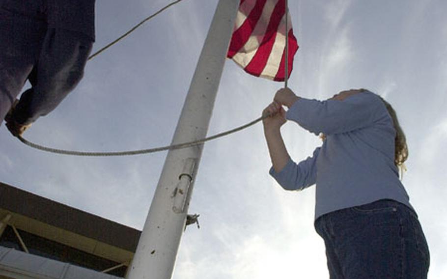 Justin Hamilton (left) and Emily Carroll, students at Shirley Lanham Elementary School on Naval Air Facility Atsugi, Japan, help raise Old Glory during a special presentation Friday at the school.