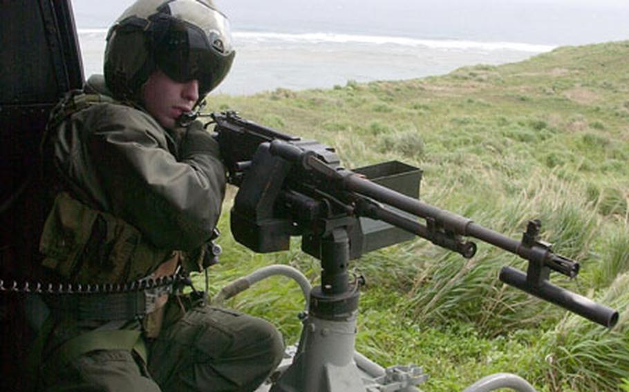 Marine Cpl. Paul O&#39;Brien, of Marine Light Attack Squadron 367 and a crew chief on a UH-1N Huey, fires his M-240G machine gun during hot insert and extract drills off the coast of Okinawa.