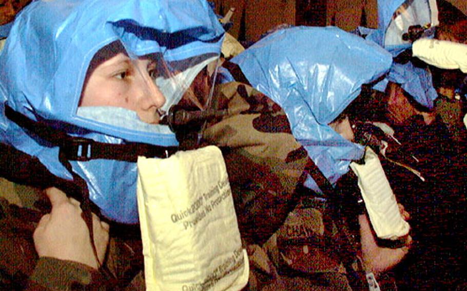 The Defense Department has planned about 50 sessions to train the roughly 24,000 Pentagon employees on how to don protective masks in the event of a chemical or biological attack. Top: At one of the first sessions, Army Sgt. Carrie Fox, left, and Sgt. Lita Chavarria unwrap and inspect their training protective hoods. Middle: The two then follow step-by-step instructions on donning a protective hood and bite down on the mouth piece. Bottom: Finally, Fox adjusts the neck cuff of the training protective mask.