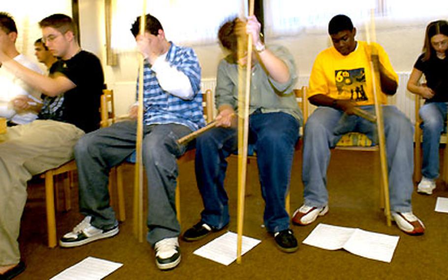 Participants in "Beyond Hum-Drum,” a workshop using percussion instruments, pound out the rhythm by beating a broomstick with a drumstick.