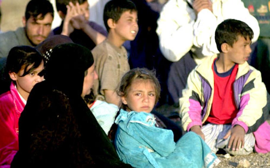 Travelers neaAs Samawah, Iraq, wait as civilian vehicles are inspected by U.S. troops.