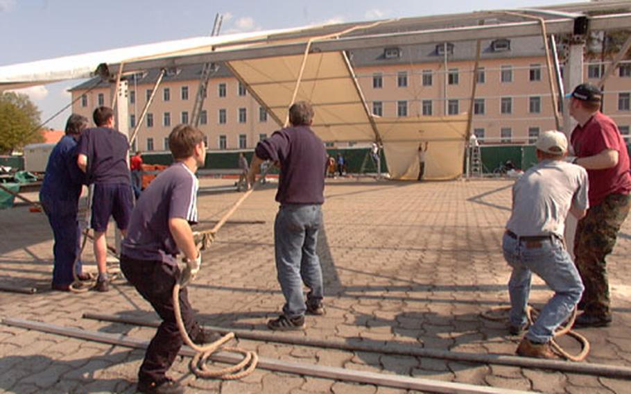 Workers pull sheets of canvas across the roof of what will be the beer tent for Warner Barracks’ German/American Volksfest on Tuesday. The fest begins Wednesday afternoon, and is open to the public.