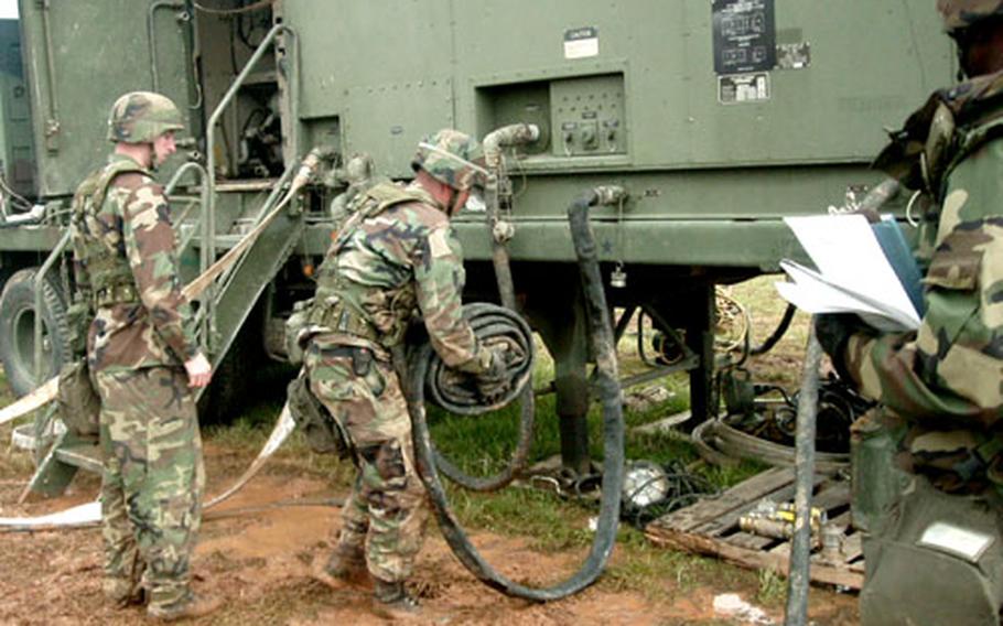 Army Pfc. Scott Starnes, left, and Sgt. Joshua Duitman, both of the 305th Quartermaster Company, hustle to set up water purification equipment.