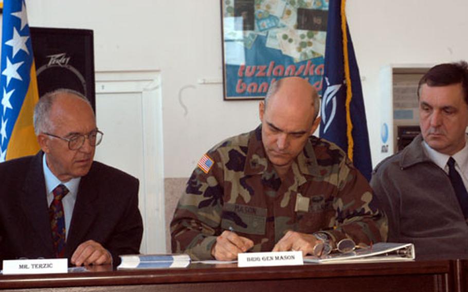 Mustafa Terzic, general manager of Tuzla International Airport, left, looks on as Brig. Gen. James Mason, commander of Multinational Brigade North, signs one of the documents which made the civilian airport reopening possible. The airport which was shut down after the Sept. 11 terrorist attacks for security reasons, and was reopened Wednesday in a ceremoney attended by SFOR, local government officials and airport staff.