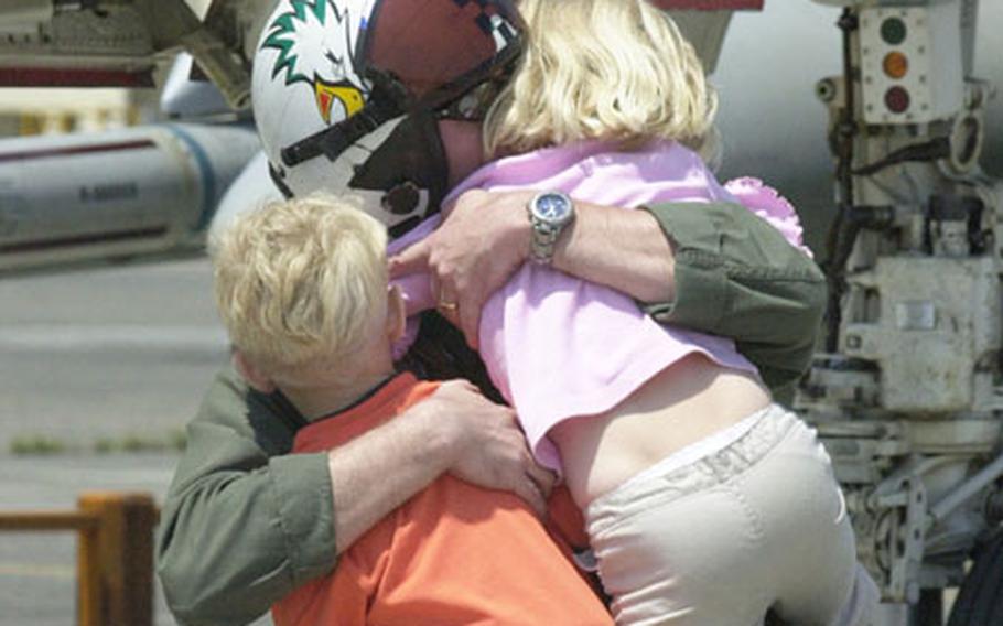 A pilot from Fighter Squadron 195 hugs his children upon his arrival home to Atsugi Naval Air Facility.