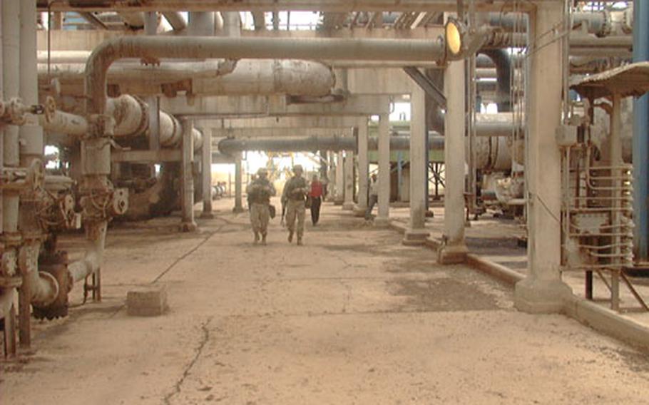 Surrounded by a symphony of hums and hisses, Maj. Robert Gowan (left) and 1st Lt. Brian Nash of the 173rd Airborne Brigade, Vicenza, Italy, walk through a corridor of pipes at the large oil facility north of Kirkuk in northern Iraq. Despite the infrastructure&#39;s shaky state, the facility is working, pumping 60,000 barrels of oil a day. At its peak, the facility&#39;s daily output was 280,000 barrels.