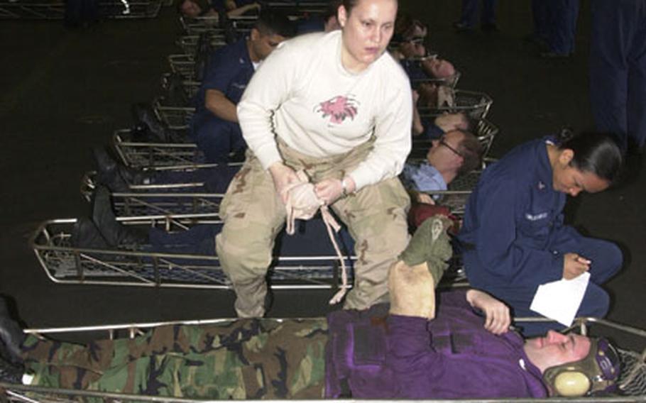 Medical staff from the USS Kitty Hawk treat a long row of simulated casualties in the main hangar bay. Without port calls, the trip home has been full of exercises and drills.