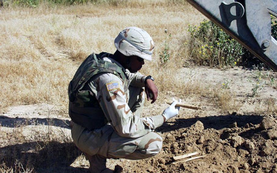 Sgt. Terrance Dailey, a mortuary affairs specialist with the 201st Forward Support Battalion from Vilseck, Germany, examines some human bones unearthed Friday at a mass grave near Kirkuk, Iraq.