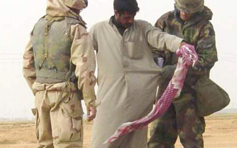 A soldier from the 527th Military Police Company, from Giessen, Germany, conducts a body search on an Iraqi citizen during a random checkpoint in southern Iraq as a translator watches.