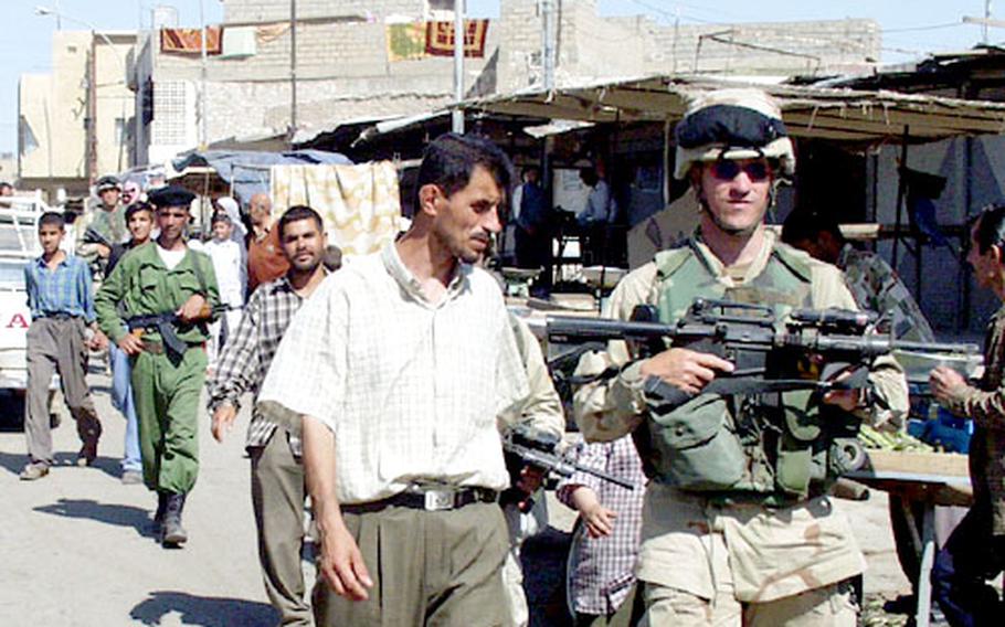 Capt. Arie Richards, commander of Company C, 2nd Battalion, 503rd Infantry Regiment, and a local police officer patrol the market at Kirkuk, Iraq. The Army started the joint patrols with local police last week.