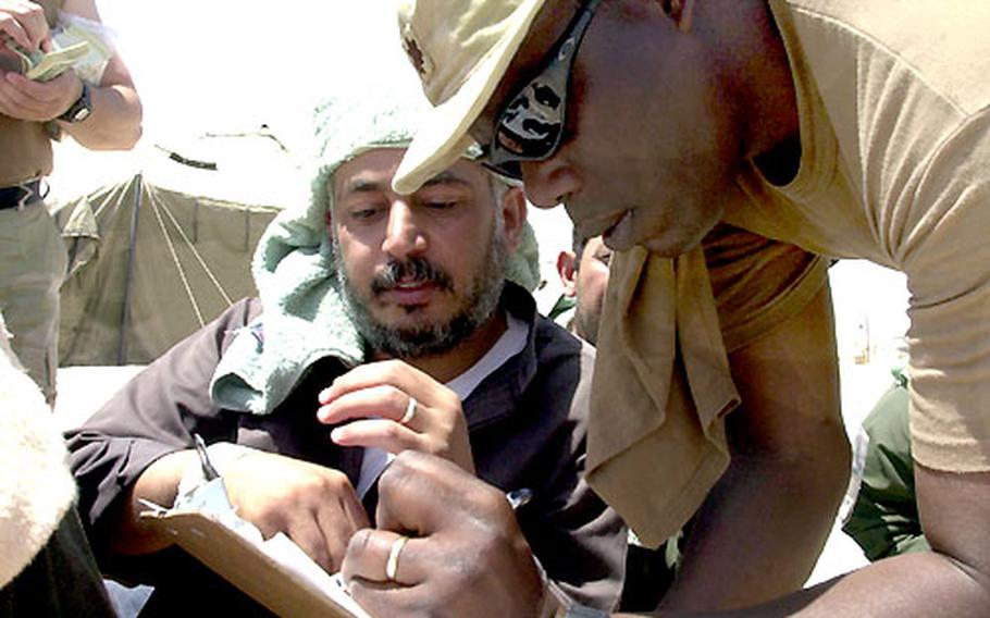 Maj. Marshall Bacote checks an Iraqi man off his list Tuesday during a release of prisoners at Camp Bucca.