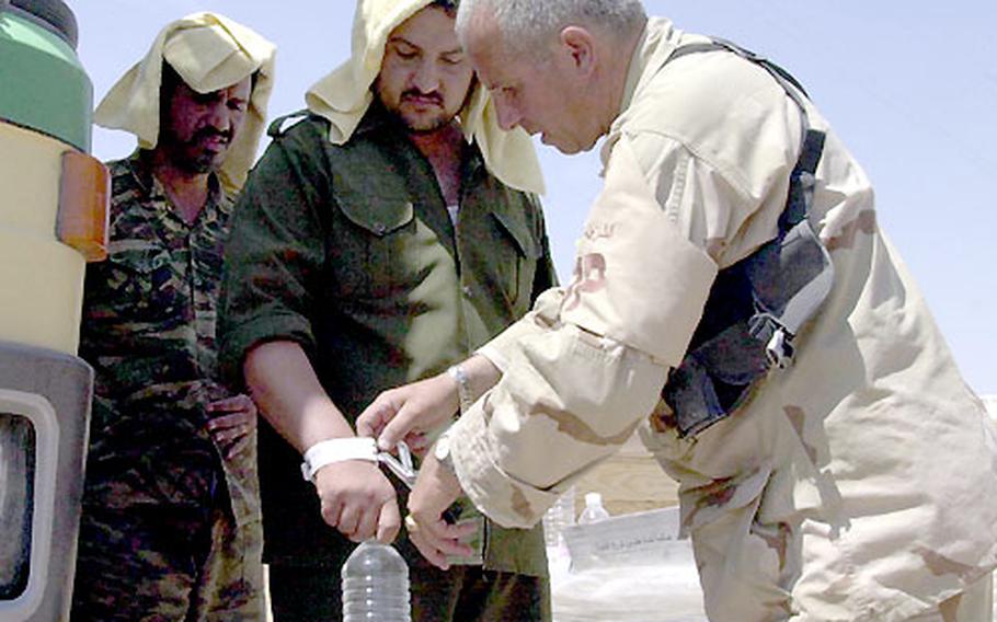 Cutting the identification bracelet from an Iraqi prisoner, 800th Military Police Brigade 1st Sgt. Mickey Michelino, of New York, N.Y., frees the former captive and directs him to a nearby bus. Each prisoner received food, water, cigarettes and $5 cash.