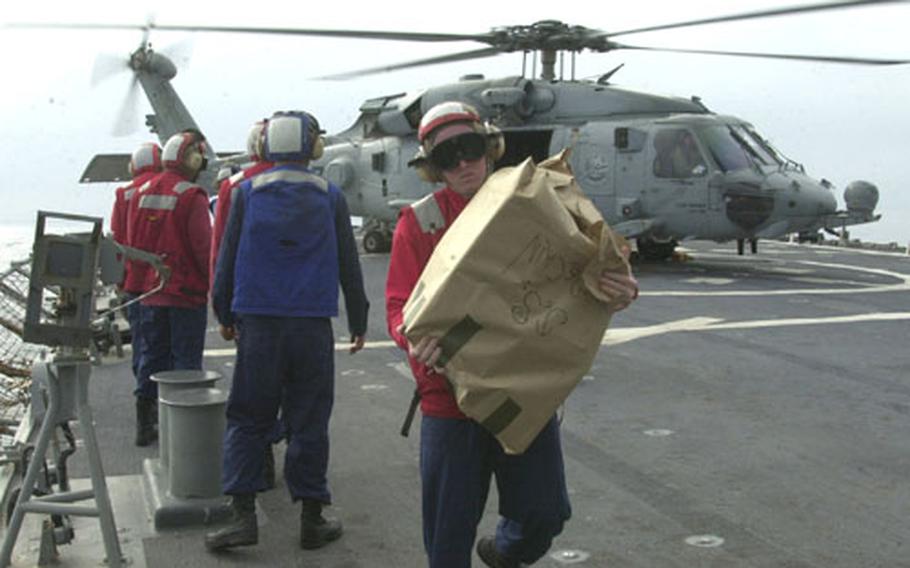 Sailors from the USS John S. McCain carry in spare parts brought on board by helicopter. The McCain returned to Yokosuka on May 6 after a long deployment to the Persian Gulf.