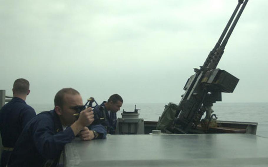 Ensign William Carr (foreground) takes a sextant reading as the USS John S. McCain approaches a Navy fueler off the coast of Japan. The McCain returned from the Persian Gulf on May 6.