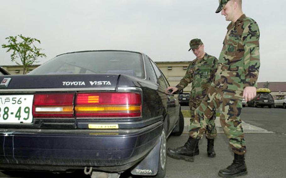 Like any prospective car owner, Airman 1st Class Aaron Bethard kicks the wheels of a Toyota Vista as owner, Senior Amn. William Miller, watches. Miller is donating his high-mileage car free of charge to Bethard under a new program sponsored by Misawa’s First Term Airmen’s Center.