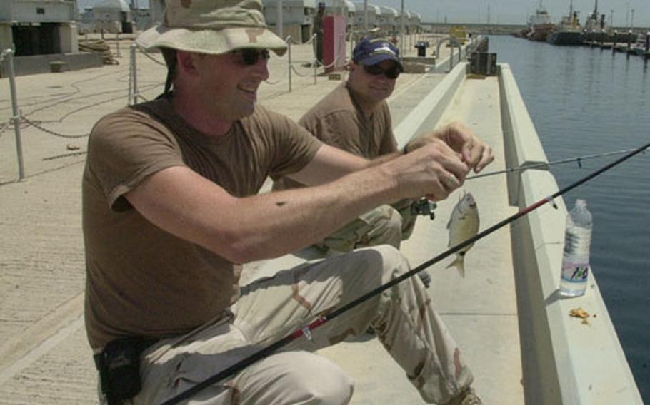 Petty Officer 2nd Class Robert Wilmot, 34, of Portland, Ore., catches a small fish at Camp Patriot Kuwait, as fellow sailor Petty Officer 2nd Class Robert Hayes, 32, of Corona, Calif., watches. The sailors have been part of the harbor patrol at the base, about 30 miles south of Kuwait City.