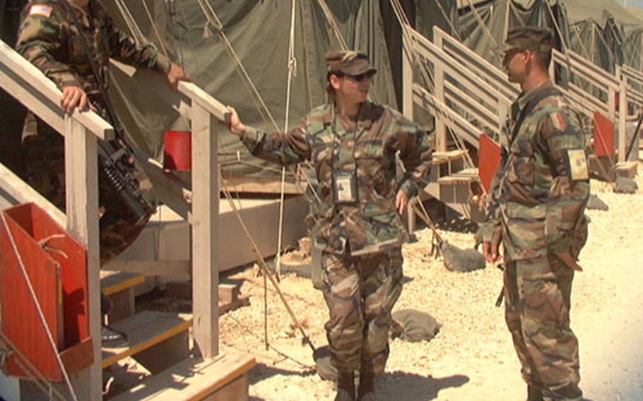 Sgt. Leandro Diaz, translator Eve Niceva and Pvt. Philip Robertin talk outside one of the living areas at Camp Bondsteel in Kosovo. Military commanders are using the utilitarian post as a model for new bases planned for Eastern Europe.