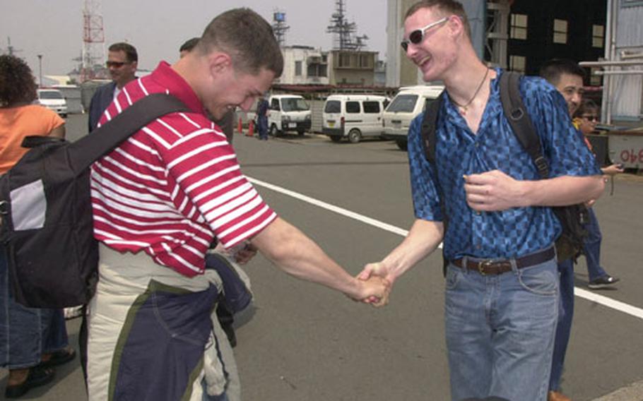With a hearty and gregarious handshake after being apart for 1½ years, the USS Carl Vinson’s Petty Officer 3rd Class Richard Shilling, left, greets his older brother, Petty Officer 3rd Class Matthew Shilling of the USS Kitty Hawk, on Saturday at Yokosuka Naval Base’s Pier 3.