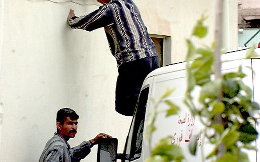 When it comes to health care needs in Iraq, shortages come in all shapes and sizes. For these two maintenance workers at Kirkuk General Hospital in northern Iraq, they’re short a ladder, so they improvise by using the hood of an ambulance to fix an outdoor light.