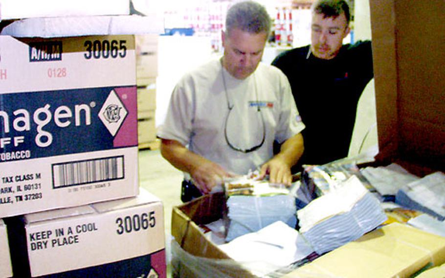 Dennis Hatcher, manager for the Army and Air Force Exchange in Iraq, and worker Fritz Eischenhauer check out a shipment of magazines headed for tactical field exchanges in Iraq.