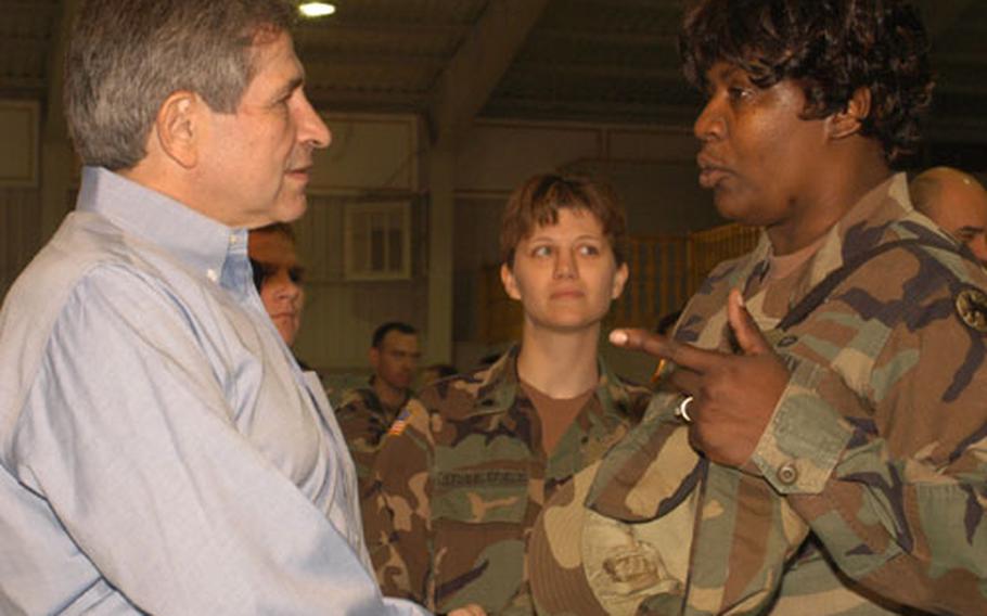 The U.S. Deputy Secretary of Defense, Paul Wolfowitz, left, shakes hands with Staff Sgt. JoAnn Brown of Task Force Medical Eagle, right, during his visit to Bosnia on Armed Forces Day. He signed the arm cast of Spc. Jennifer Stubblefield of 35th Military Police Company, center.