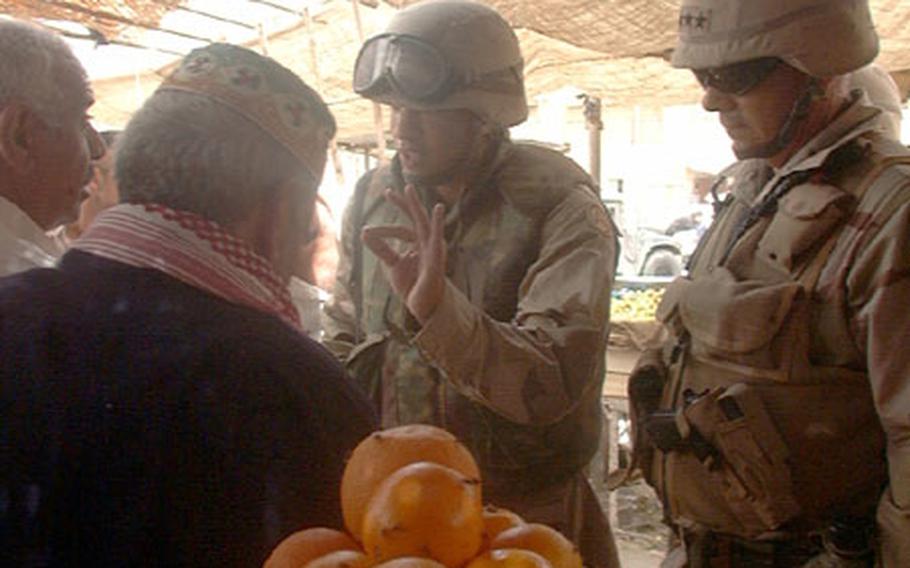 V Corps Commander Lt. Gen. William S. Wallace, with the help of interpreter Sgt. Daeman Harris, talks with a leader at a market in the Hi-Salam area of northwest Baghdad.