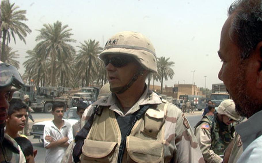 V Corps Commander Lt. Gen. William S. Wallace talks with an Iraqi merchant in Hi-Salam, a Shiite neighborhood in northwest Baghdad. Wallace sent Army medics, seen in background, and engineers to the neighborhood to treat people and clean up the area.