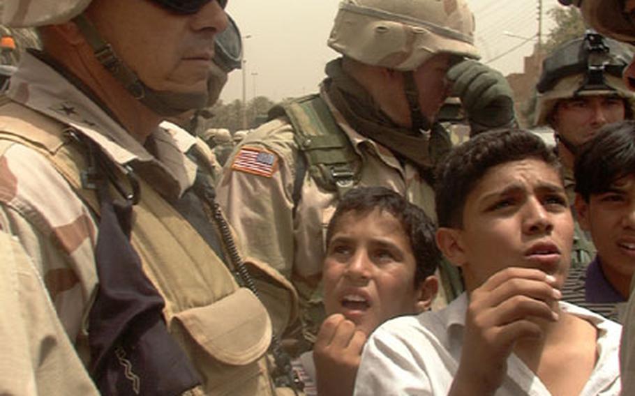 V Corps Commander Lt. Gen. William S. Wallace listens to a boy talking about shortages of school supplies in his northwest Baghdad school.